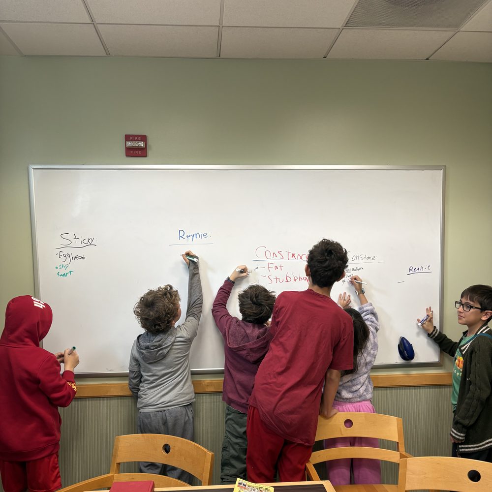 Kids brainstorming character traits on a whiteboard during book club